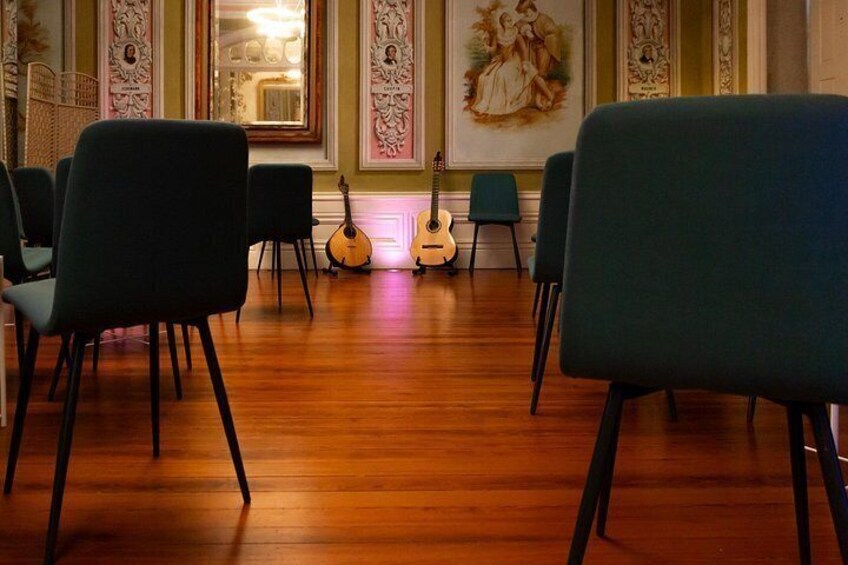 A room with wooden flooring, green chairs, and a guitar. 2