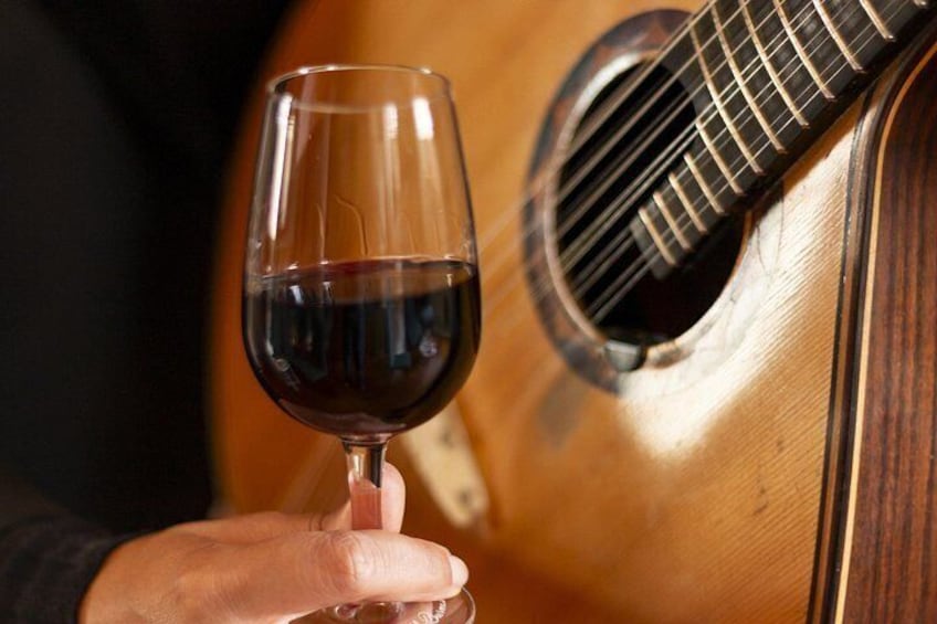 A hand holding a wine glass next to a guitar. 4
