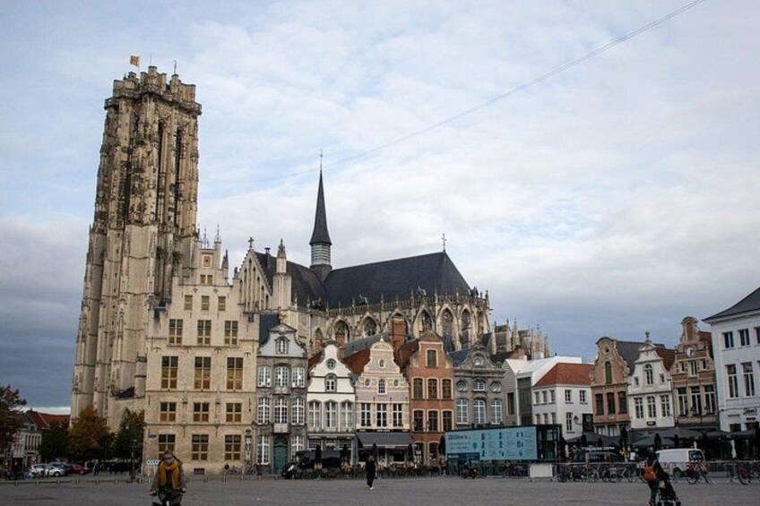 Un edificio histórico con una torre alta y una aguja, rodeado de arquitectura europea tradicional. 2