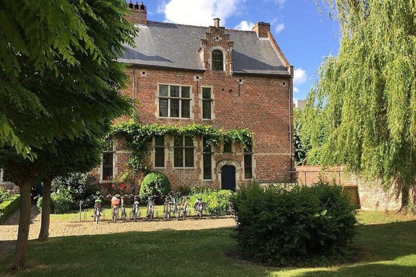 Un bâtiment en briques avec un jardin, un arbre et un vélo. 2