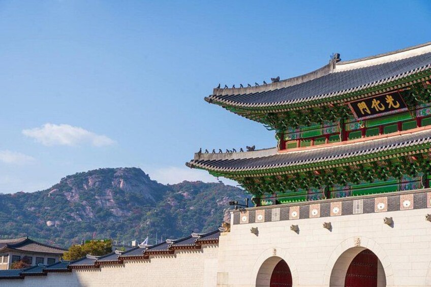 Een traditioneel Koreaans gebouw met een meerlaags dak en een bergachtig landschap op de achtergrond. 1