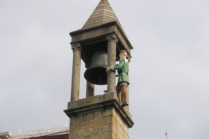Een klokkentoren met een standbeeld van een man die aan een bel trekt. 2