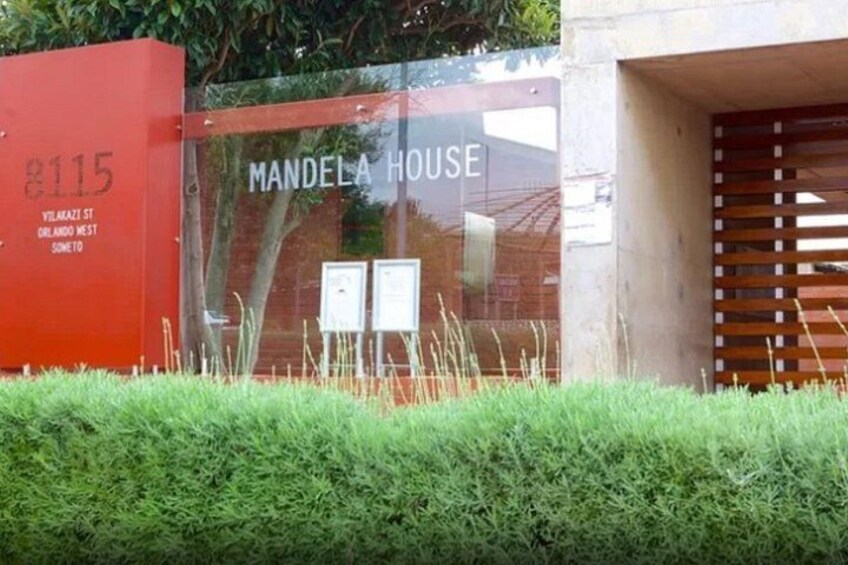 Un edificio con un letrero que dice 'Mandela House' y una pared roja con el número '8115'. 5