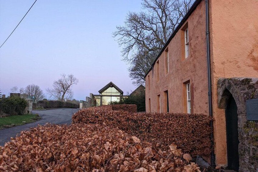 A rural street with a pile of leaves, a stone wall, and a building with a sloped roof. 3