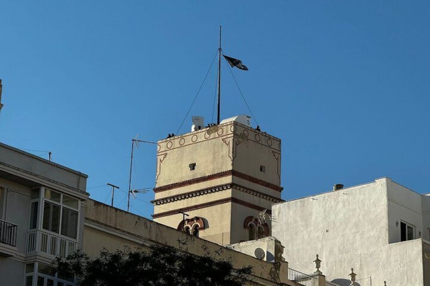 Una torre con una bandera, rodeada de edificios. 1