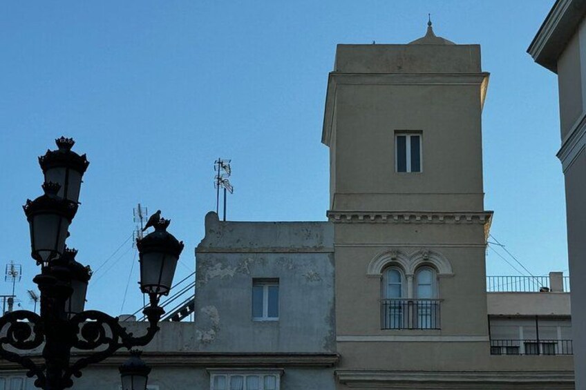 A building with a tower, a street lamp, and a clear blue sky. 3