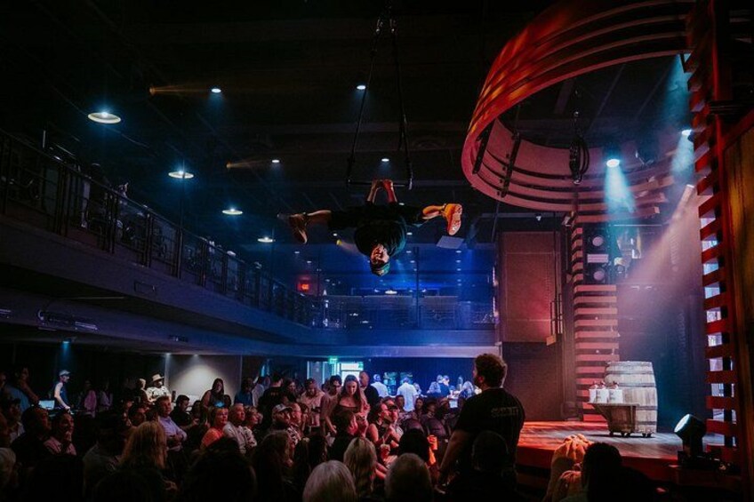 A crowded indoor event with a stage and a large audience. 1