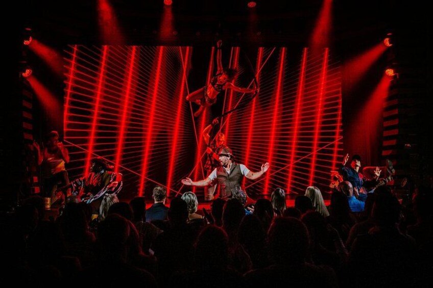 A band performing on a stage with red lighting and a large audience. 2
