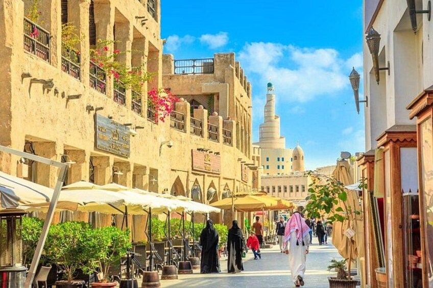 Eine belebte Straße mit traditioneller Architektur, Straßencafés und einem markanten Minarett im Hintergrund. 4