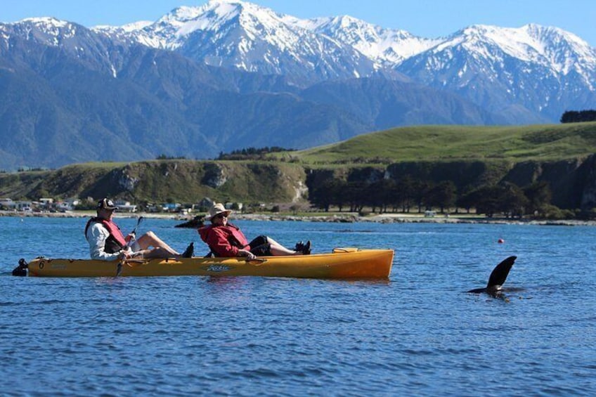 Two people kayaking on a calm lake with mountains in the background. 2
