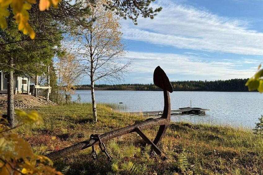 A lake with a dock, a metal sculpture, and a house in the background. 4