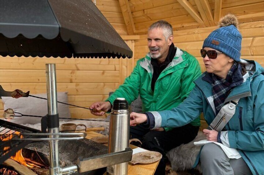 Dos personas cocinando al aire libre, usando un hornillo portátil y un recipiente metálico. 4