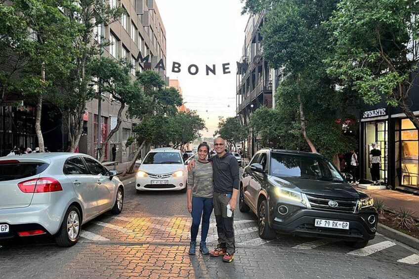 A street with parked cars, a building with 'BONE' sign, and pedestrians. 2