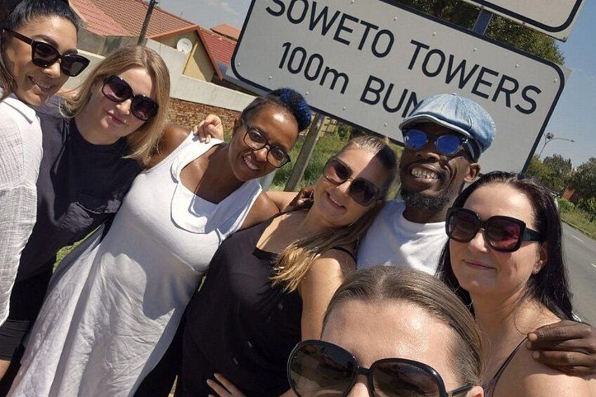 A group of people posing with a sign that reads 'SOWETO TOWERS 100m BUM.' 4