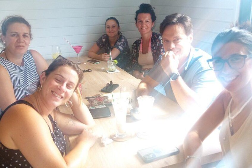 Un groupe de personnes assises autour d’une table, avec des boissons et un téléphone intelligent. 4