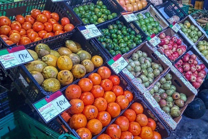 Un marché où l’on trouve différents fruits, présentés dans des caisses, notamment des oranges, des pommes et des citrons. 1