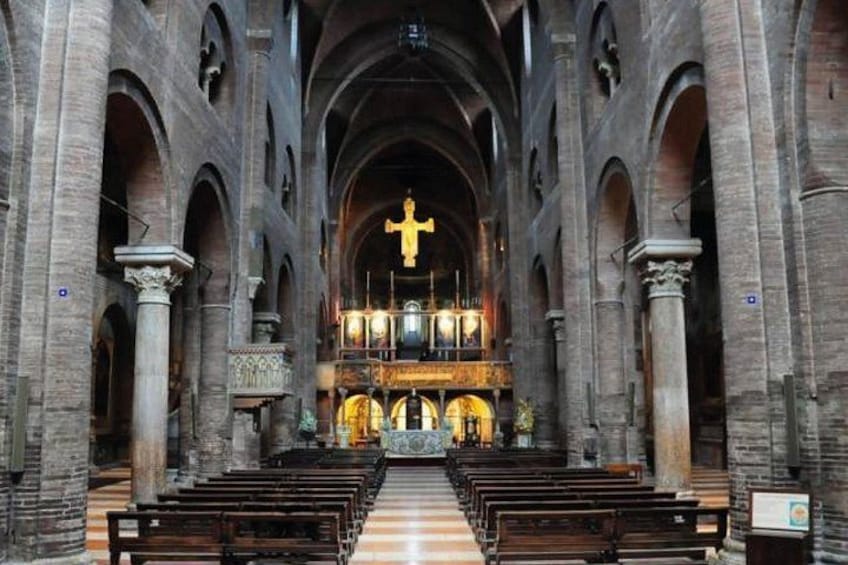 A church interior with high vaulted ceilings, rows of pews, and a central altar with a cross. 2