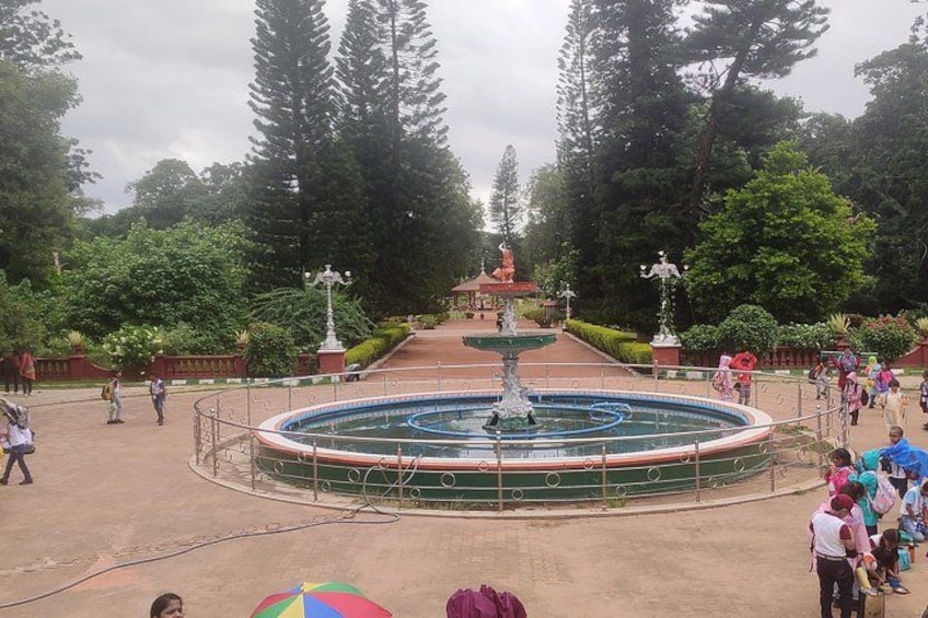 Un parque con una fuente central, rodeado de árboles y senderos. 3