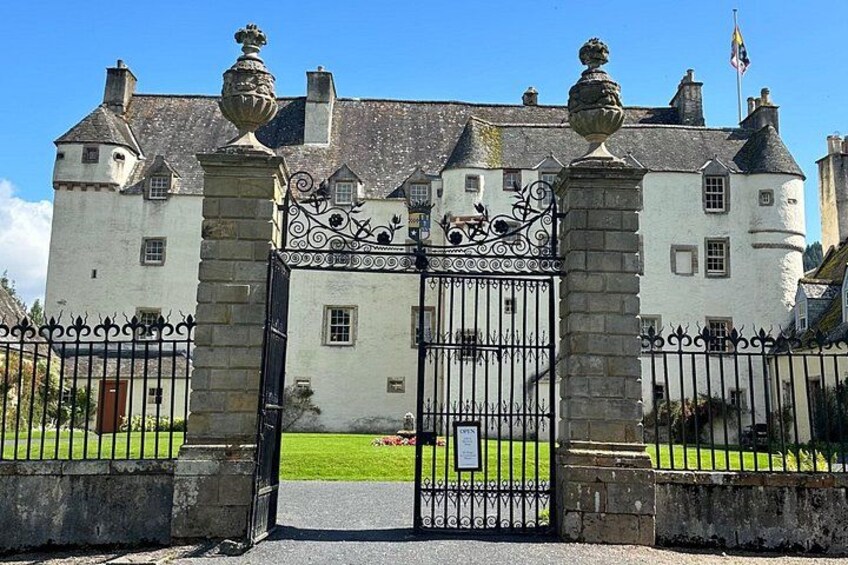 A historic building with a large iron gate, stone pillars, and a well-maintained lawn. 4