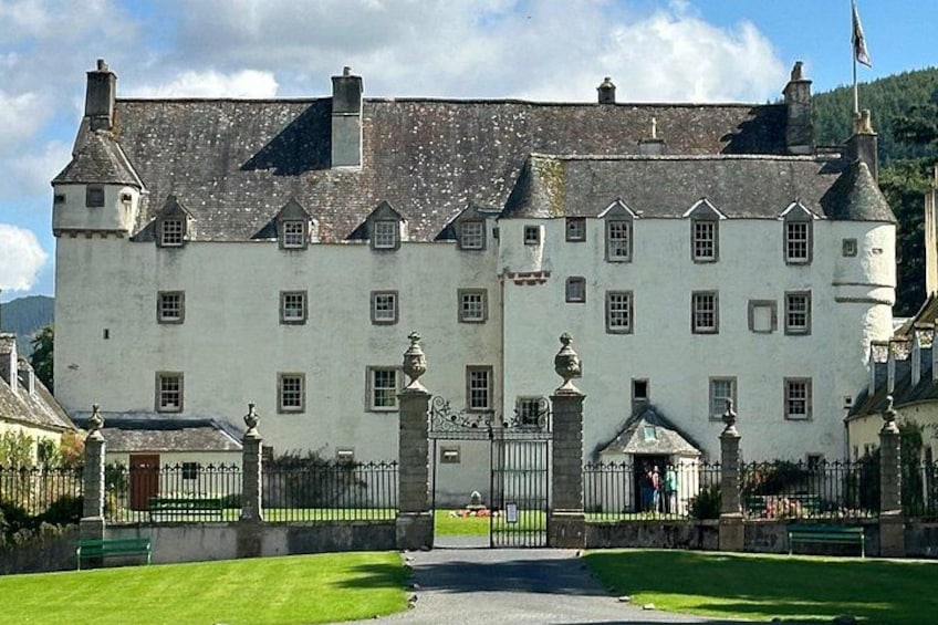 A large white building with multiple windows and a central entrance gate. 1