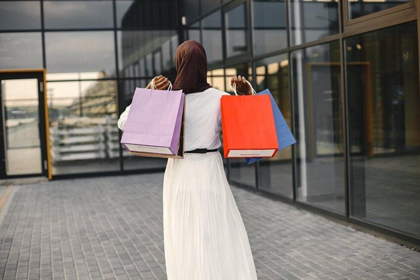 A person carrying shopping bags in front of a modern building with large glass windows. 4