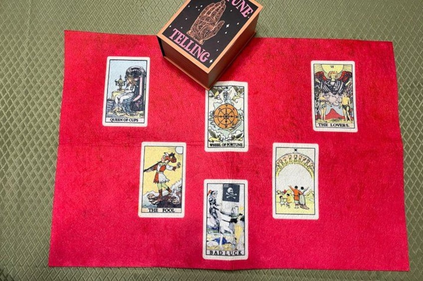 Eine rote Filzunterlage mit Tarotkarten und einer Box mit dem Aufdruck 'TELLING ONE' auf einer strukturierten Oberfläche. 5