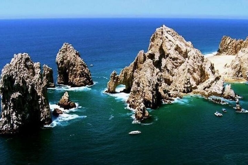A rocky coastline with clear blue waters and boats. 1