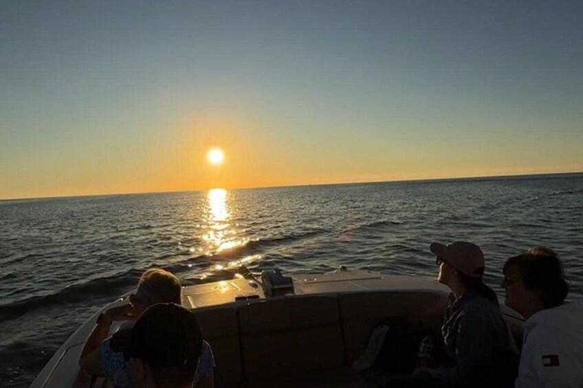 A sunset over the ocean with a boat and people on it. 3