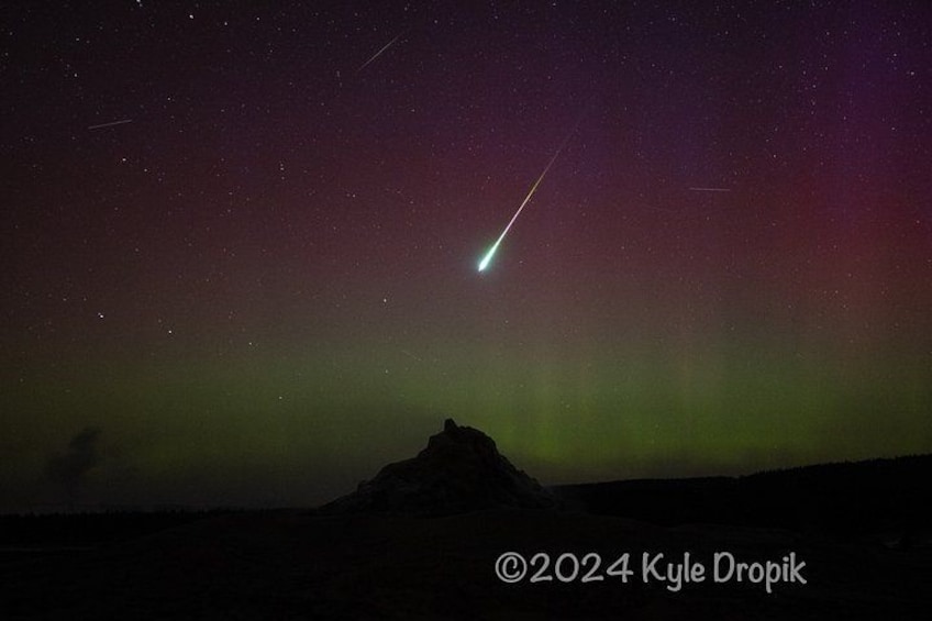 A night sky with a green aurora and a shooting star over a mountain. 5