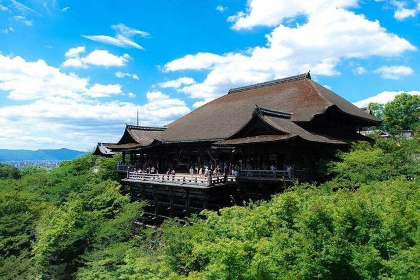 A traditional Japanese building with a sloped roof, surrounded by lush greenery and a clear blue sky. 3