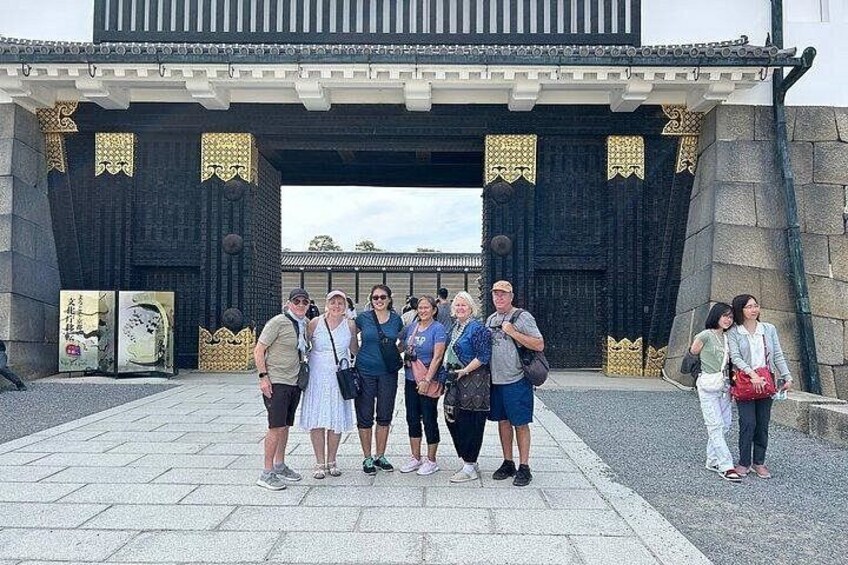 A group of people standing in front of a traditional gate with intricate designs. 4