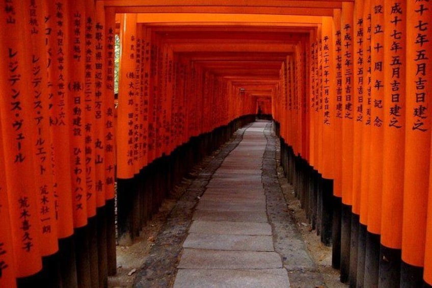 A pathway lined with orange torii gates, leading towards a shrine. 2