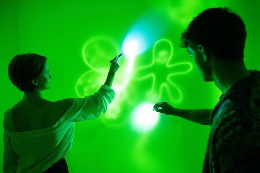 Two people interacting with a green light display. 2
