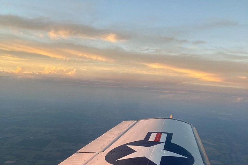 An airplane wing with a star emblem, a clear sky, and distant clouds. 4