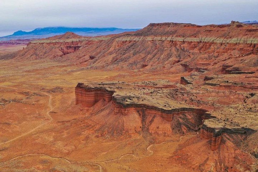Un vaste paysage désertique, avec des formations rocheuses en strates et des montagnes à l’horizon. 2