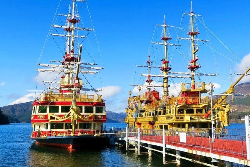 Two large, multi-decked ships docked at a pier with a mountainous landscape in the background. 4