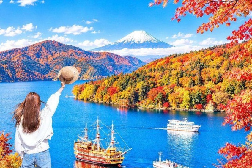 A person holding a hat, a cruise ship, and a mountain in the background. 3