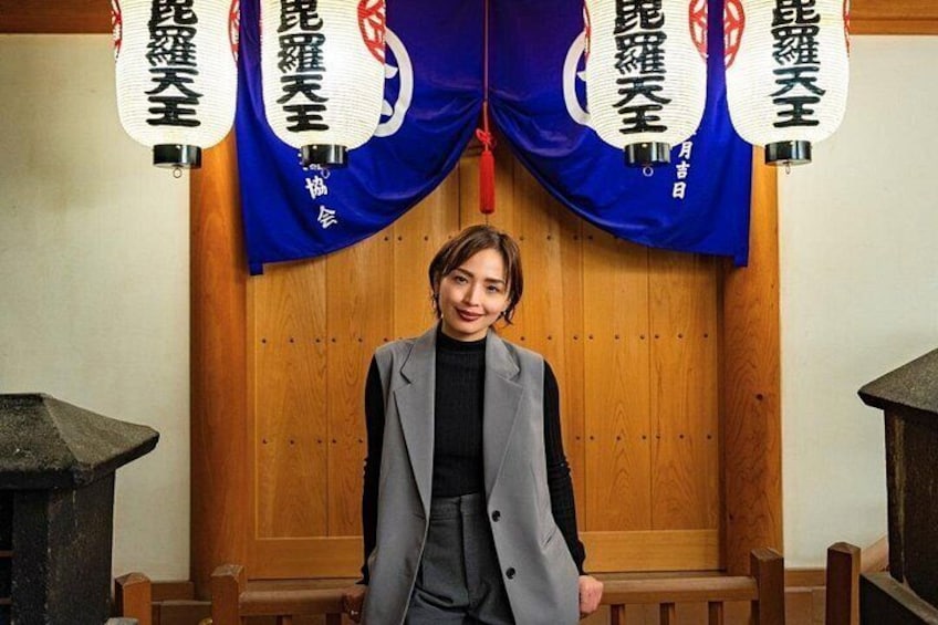 En person står foran en trækonstruktion med blå gardiner og hvide bannere med japanske tegn. 3