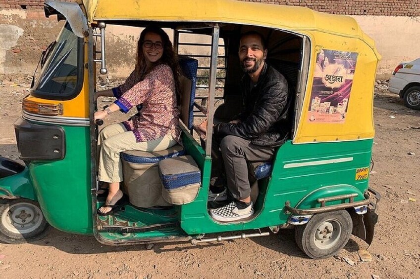 Ein Auto-Rickshaw mit zwei Fahrgästen, eine trägt ein gemustertes Oberteil und der andere eine dunkle Jacke. 1