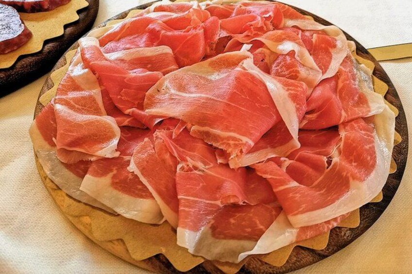 Een houten plank met plakjes parmaham. 4