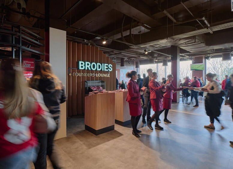 Un intérieur moderne avec un comptoir d’accueil en bois portant l’inscription « SALON DES FONDATEURS DE BROIDES », et des personnes qui interagissent dans cet espace. 3