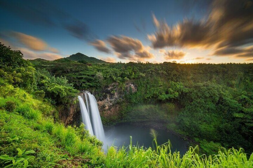 A waterfall in a lush green landscape with a clear sky. 5