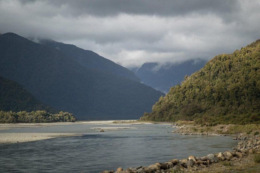 A river flowing through a mountainous landscape with dense forest on the hills. 2