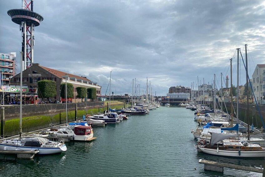A marina with boats docked along a canal, surrounded by buildings and greenery. 5