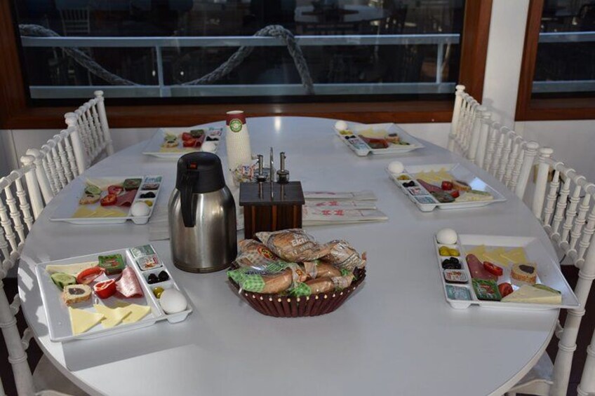 A round dining table with white chairs, a coffee pot, a fruit basket, and plates with food. 3