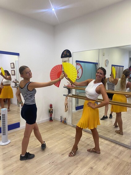 Two people in a dance studio practicing with fans. 1