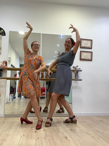 Two people in dance attire practicing in a room with a mirror and certificates on the wall. 5