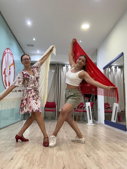 Two people dancing in a room with a wooden floor and red chairs. 2