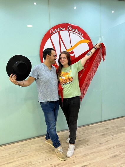 Two people standing in front of a wall with a large circular sign that reads "Caterina Gruttsina Ballet y Flamenco". 3