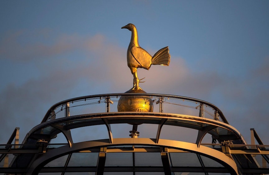 Una escultura de un pájaro dorado sobre una plataforma circular con una cubierta de vidrio. 1